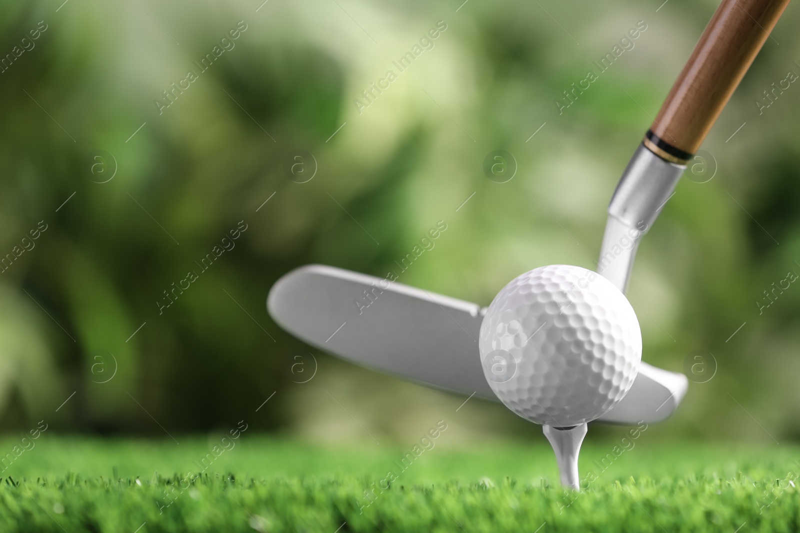 Photo of Hitting golf ball with club on artificial grass against blurred background, space for text