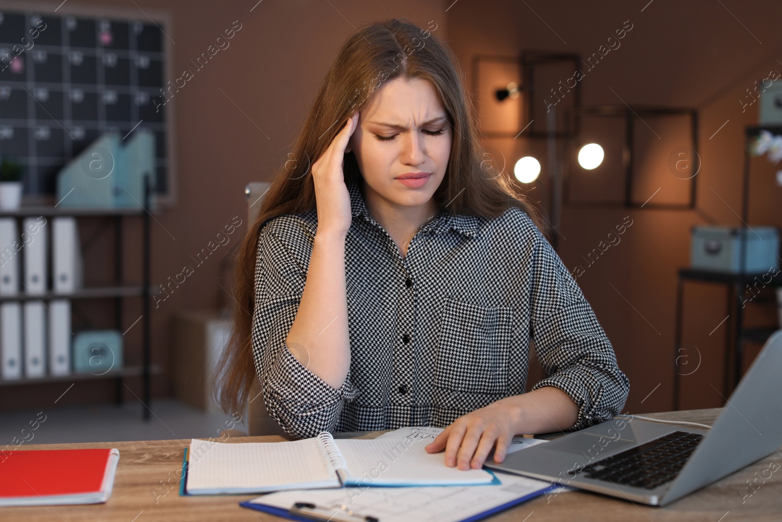 Photo of Overworked young woman with headache in office