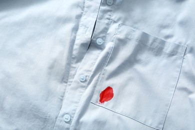 Photo of Stain of red ink on light shirt, top view. Space for text