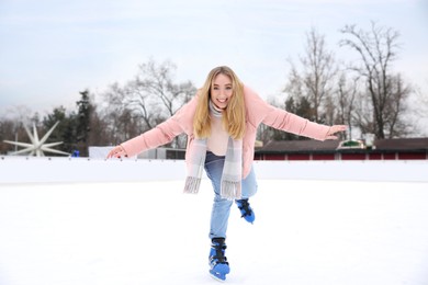 Image of Happy woman skating along ice rink outdoors