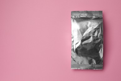 Photo of Blank foil package on pink background, top view. Space for text