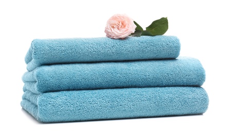 Photo of Stack of clean folded towels with flower on white background