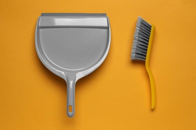 Photo of Plastic hand broom and scoop on yellow background, flat lay