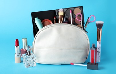 Photo of Cosmetic bag and makeup products with accessories on light blue background