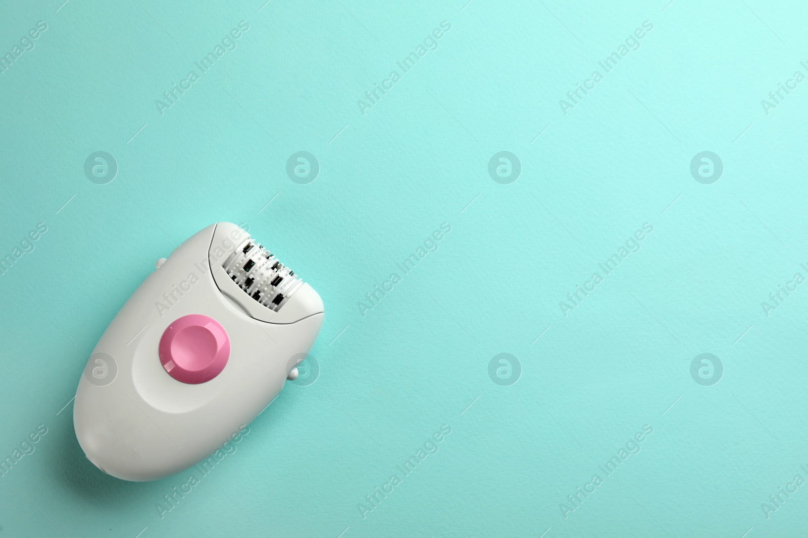 Photo of Modern epilator on turquoise background, top view. Space for text