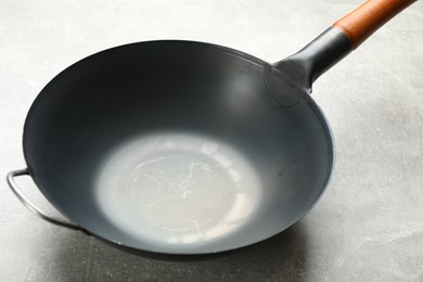 Photo of Empty iron wok on grey table. Chinese cookware