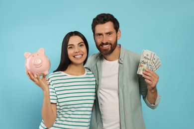 Photo of Happy couple with money and ceramic piggy bank on light blue background