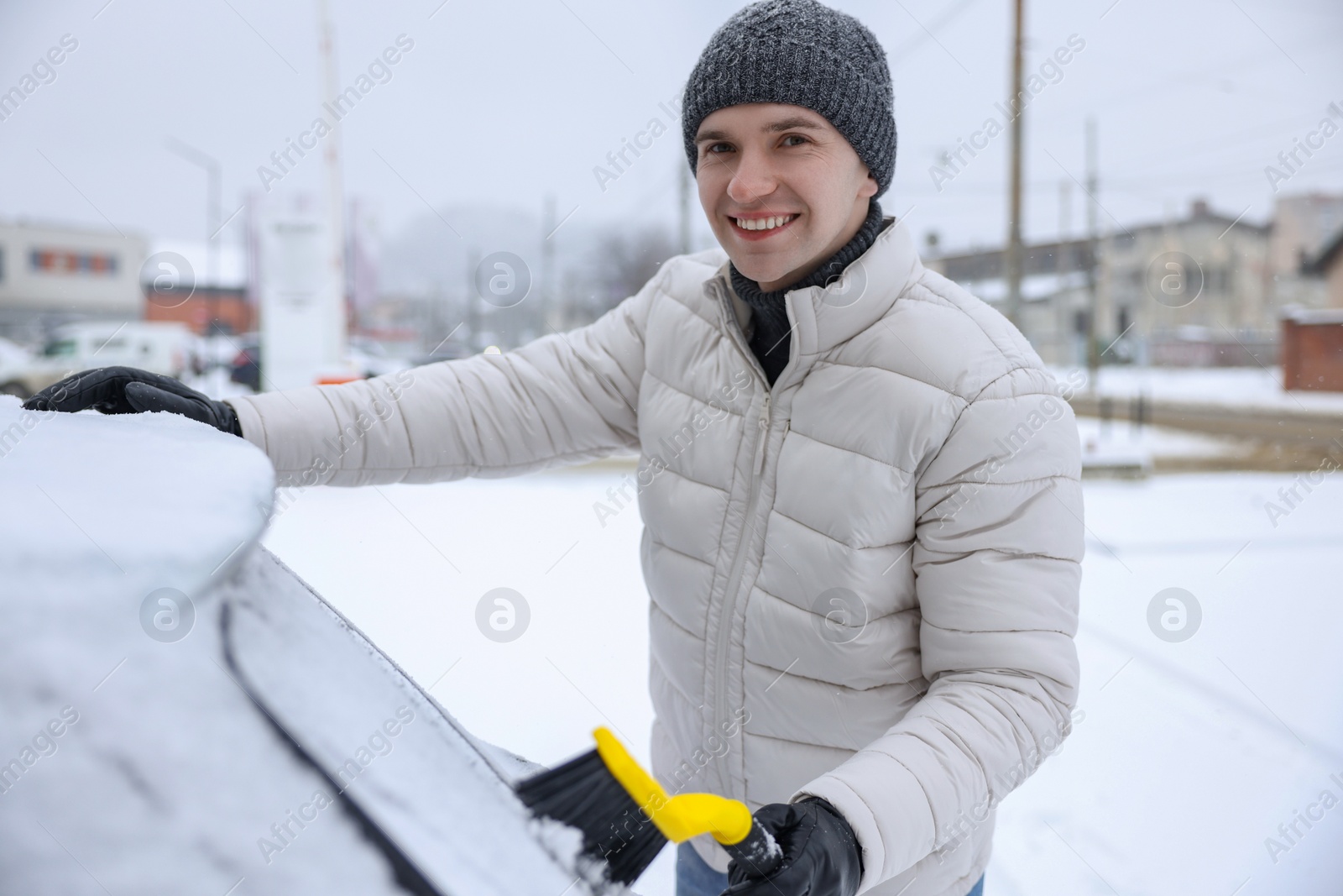 Photo of Man cleaning snow from car window outdoors