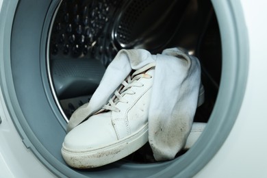 Sneakers with dirty socks in washing machine, closeup