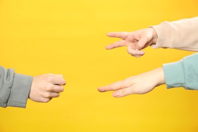 People playing rock, paper and scissors on orange background, closeup