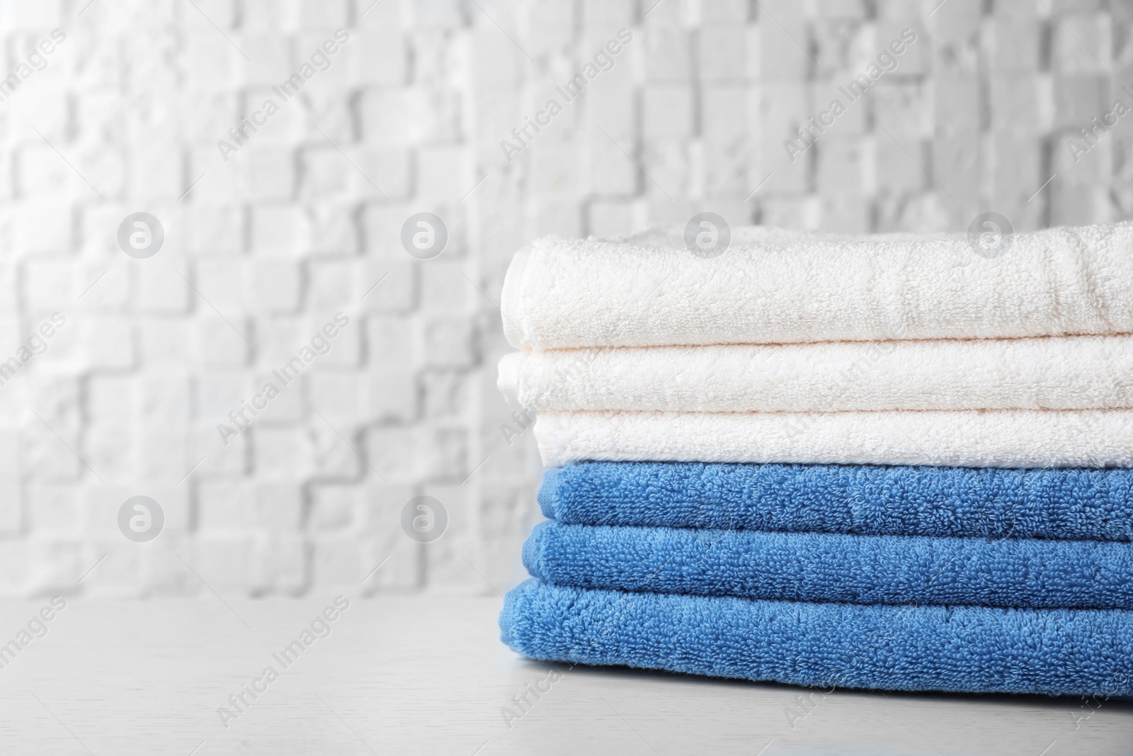 Photo of Stack of soft bath towels on table. Space for text