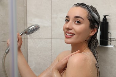 Happy woman taking shower and washing hair indoors