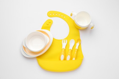 Photo of Baby feeding accessories and bib on white background, top view