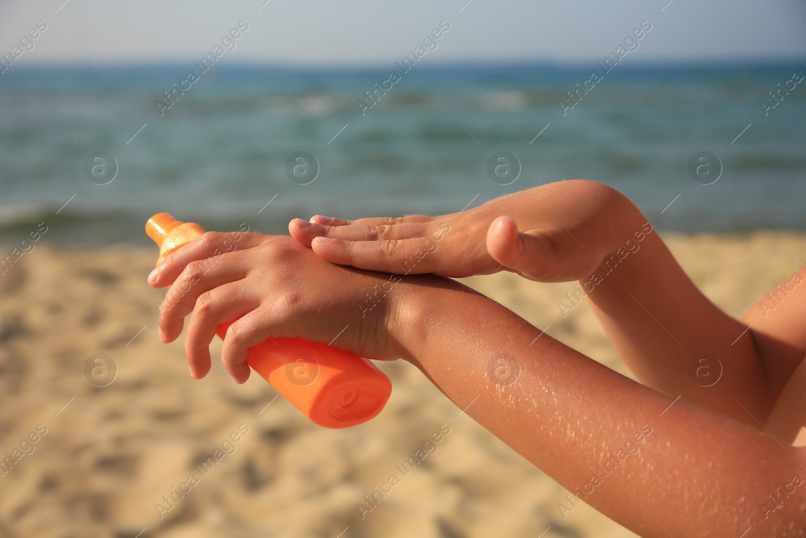 Photo of Child applying sunscreen near sea, closeup. Sun protection care