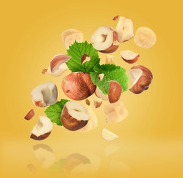 Image of Pieces of tasty hazelnuts falling on yellow background