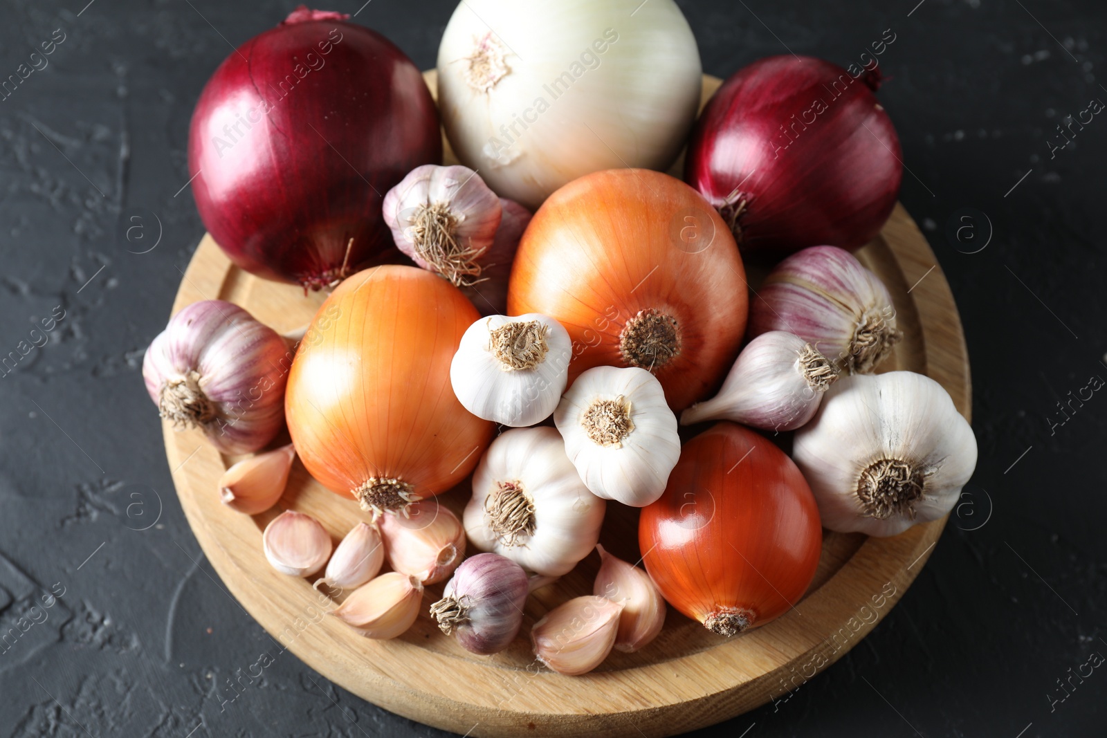 Photo of Fresh raw garlic and onions on black table, above view