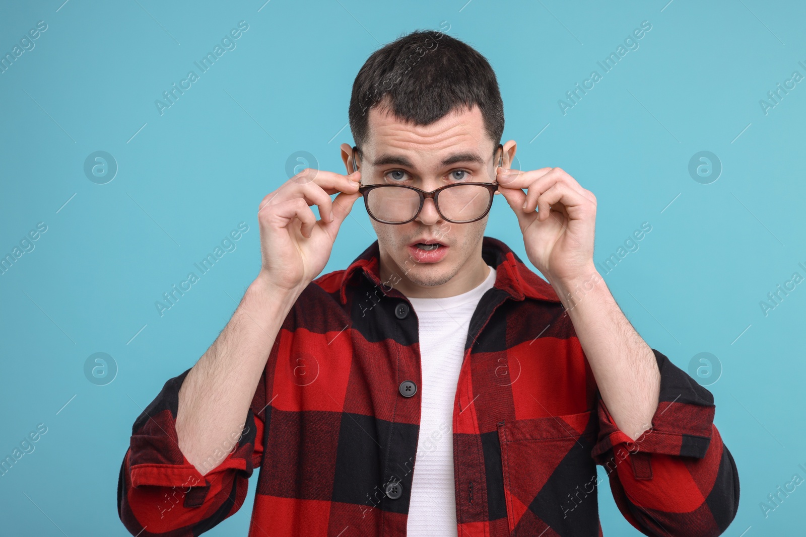 Photo of Surprised man in glasses on light blue background