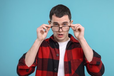 Surprised man in glasses on light blue background