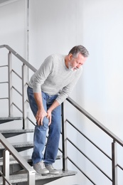 Photo of Senior man suffering from knee pain indoors