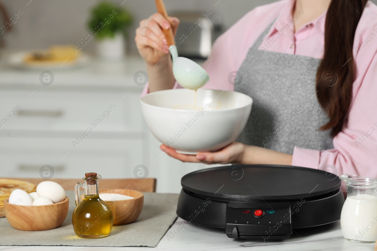 Photo of Woman with dough for crepes at white table in kitchen, closeup