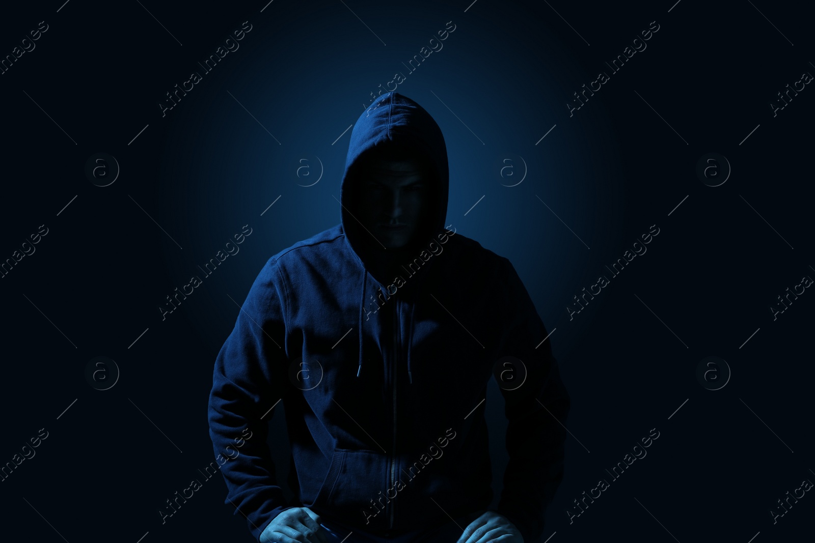 Photo of Silhouette of anonymous man on dark background, toned in blue