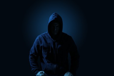 Silhouette of anonymous man on dark background, toned in blue