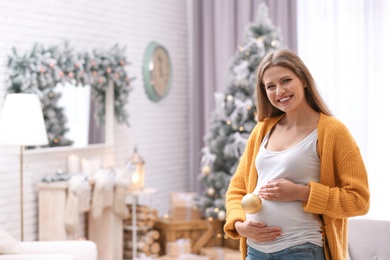 Photo of Young pregnant woman with Christmas decoration at home