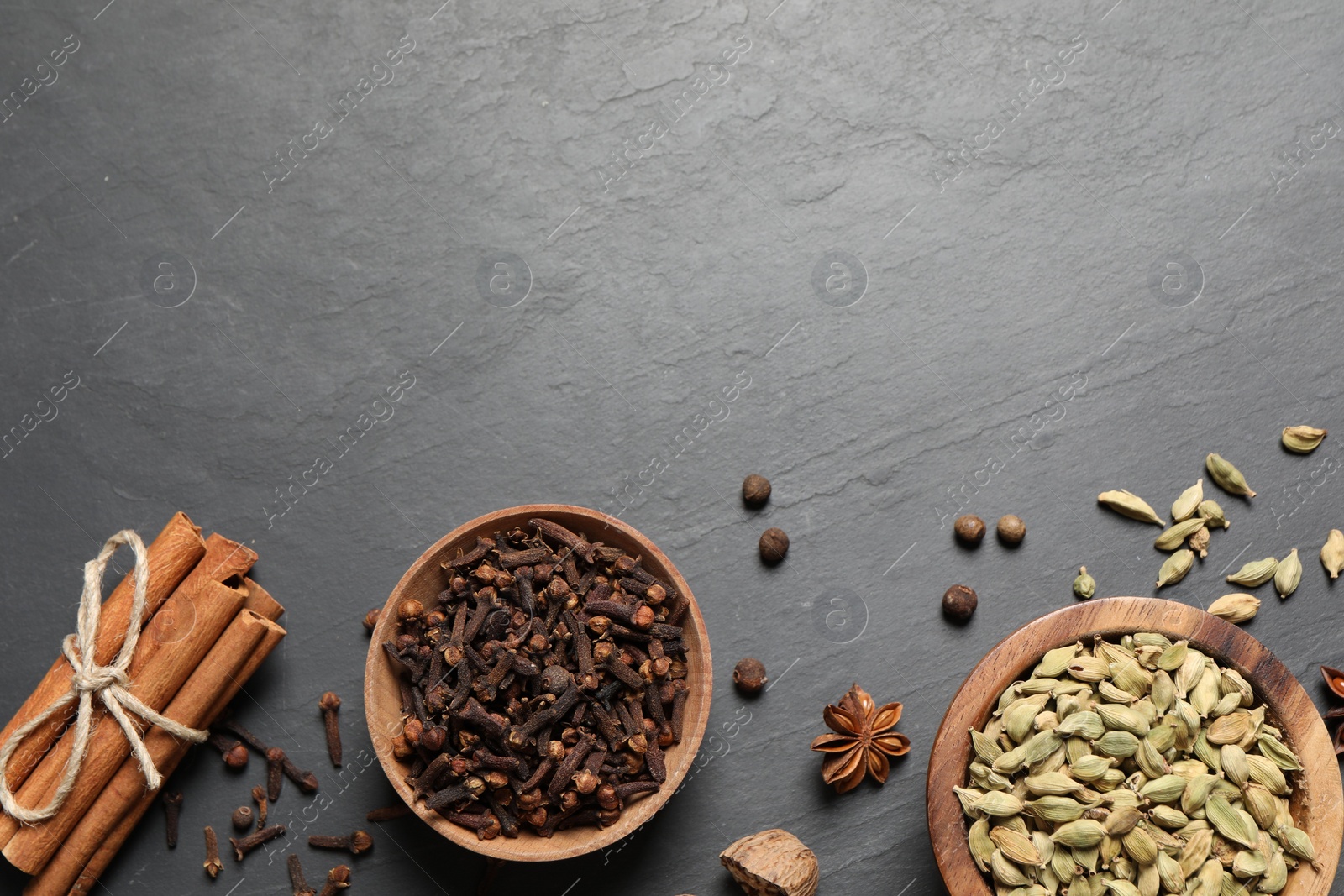 Photo of Different spices in bowls on dark gray textured table, flat lay. Space for text