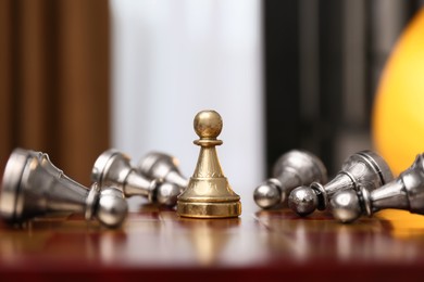Photo of Pawn piece among defeated ones on chessboard indoors