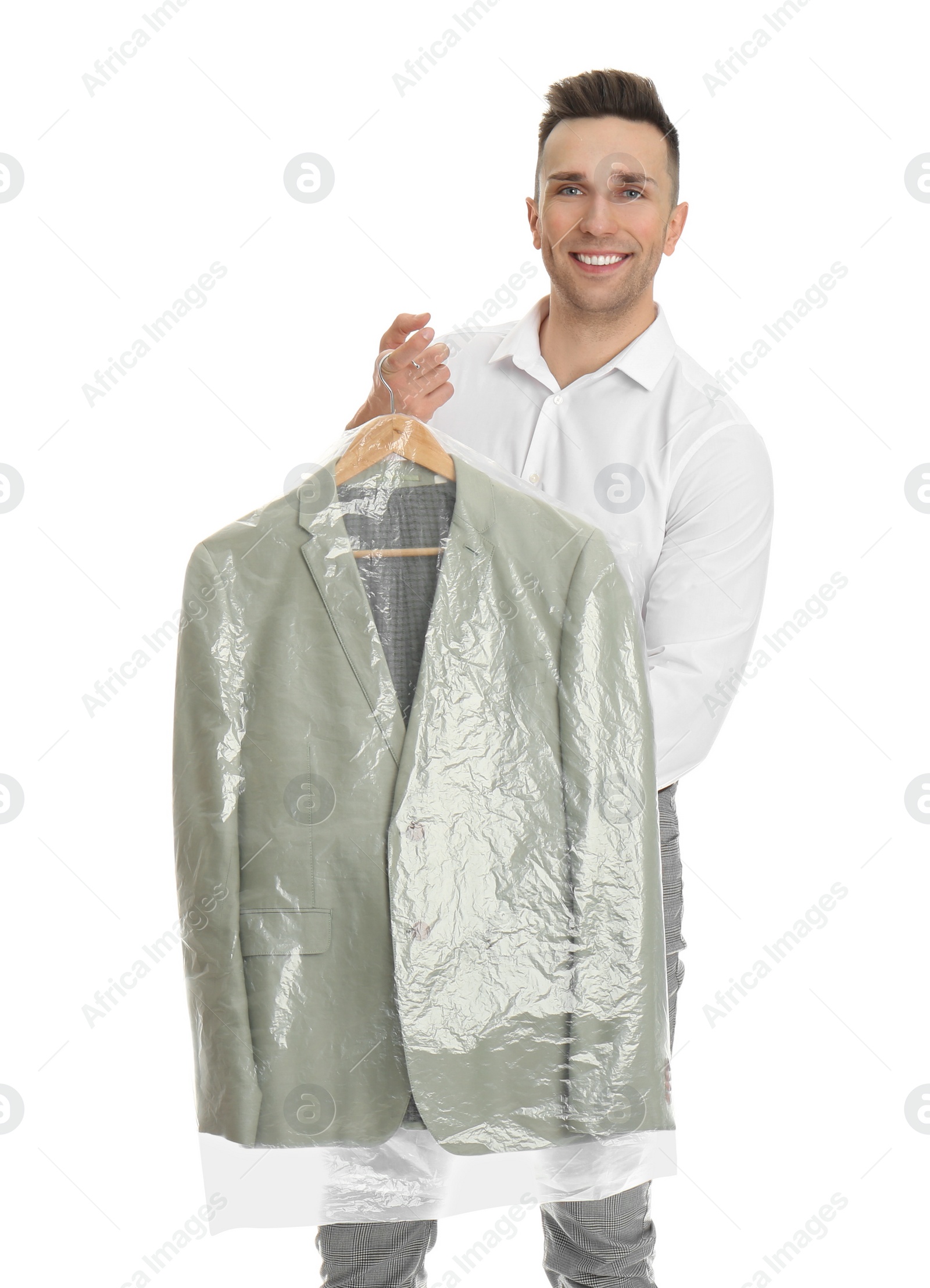 Photo of Man holding hanger with jacket in plastic bag on white background. Dry-cleaning service