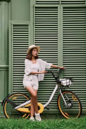 Photo of Beautiful young woman with bicycle near green wall outdoors