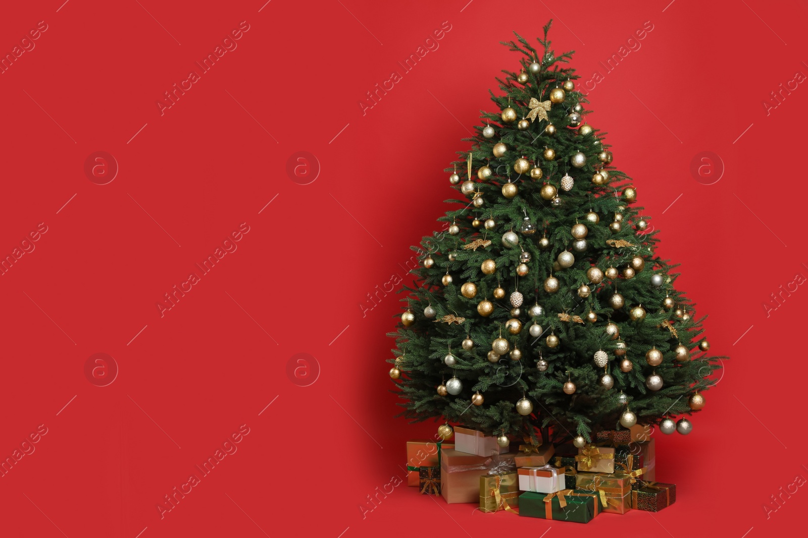 Photo of Beautifully decorated Christmas tree and many gift boxes on red background, space for text