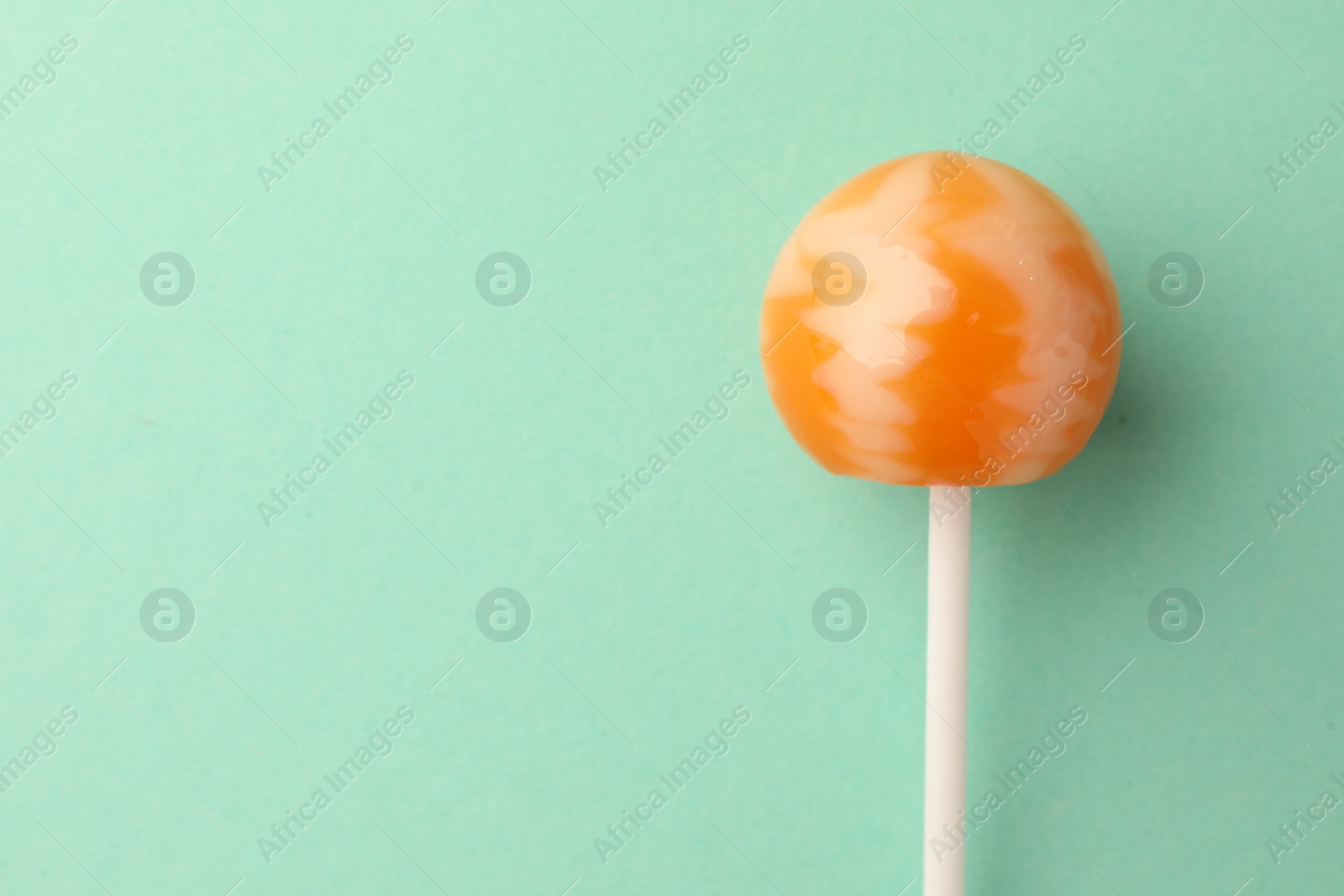 Photo of Tasty lollipop on turquoise background, top view. Space for text