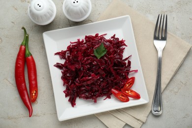 Tasty red cabbage sauerkraut with chili pepper and parsley served on light grey table, flat lay