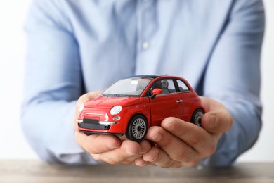 Photo of Male insurance agent holding toy car, closeup