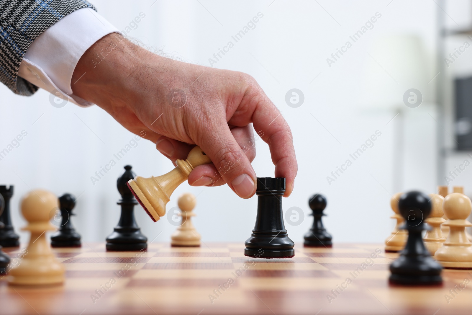 Photo of Man with rook game piece playing chess at checkerboard indoors, closeup