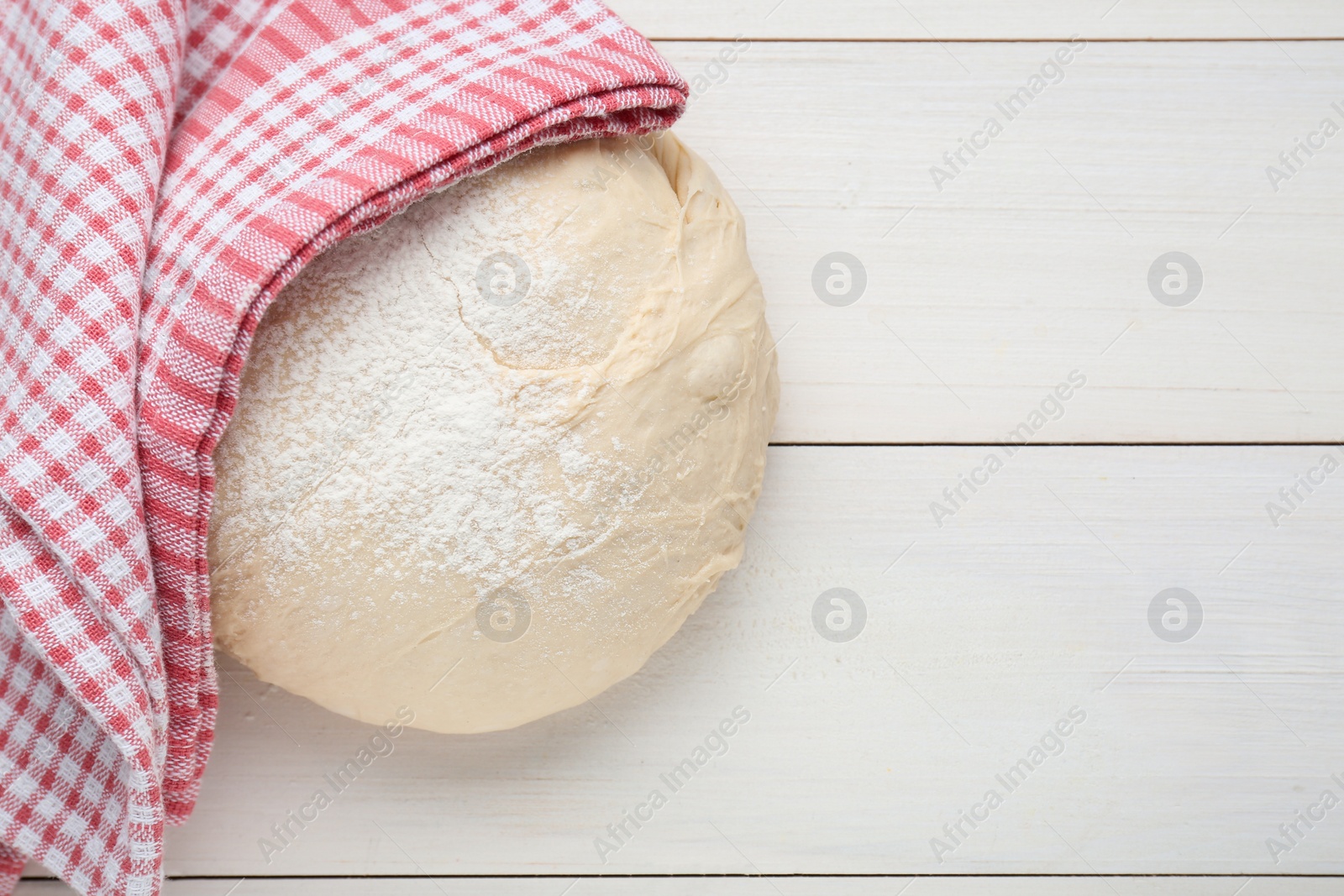 Photo of Fresh yeast dough with flour on white wooden table, top view. Space for text