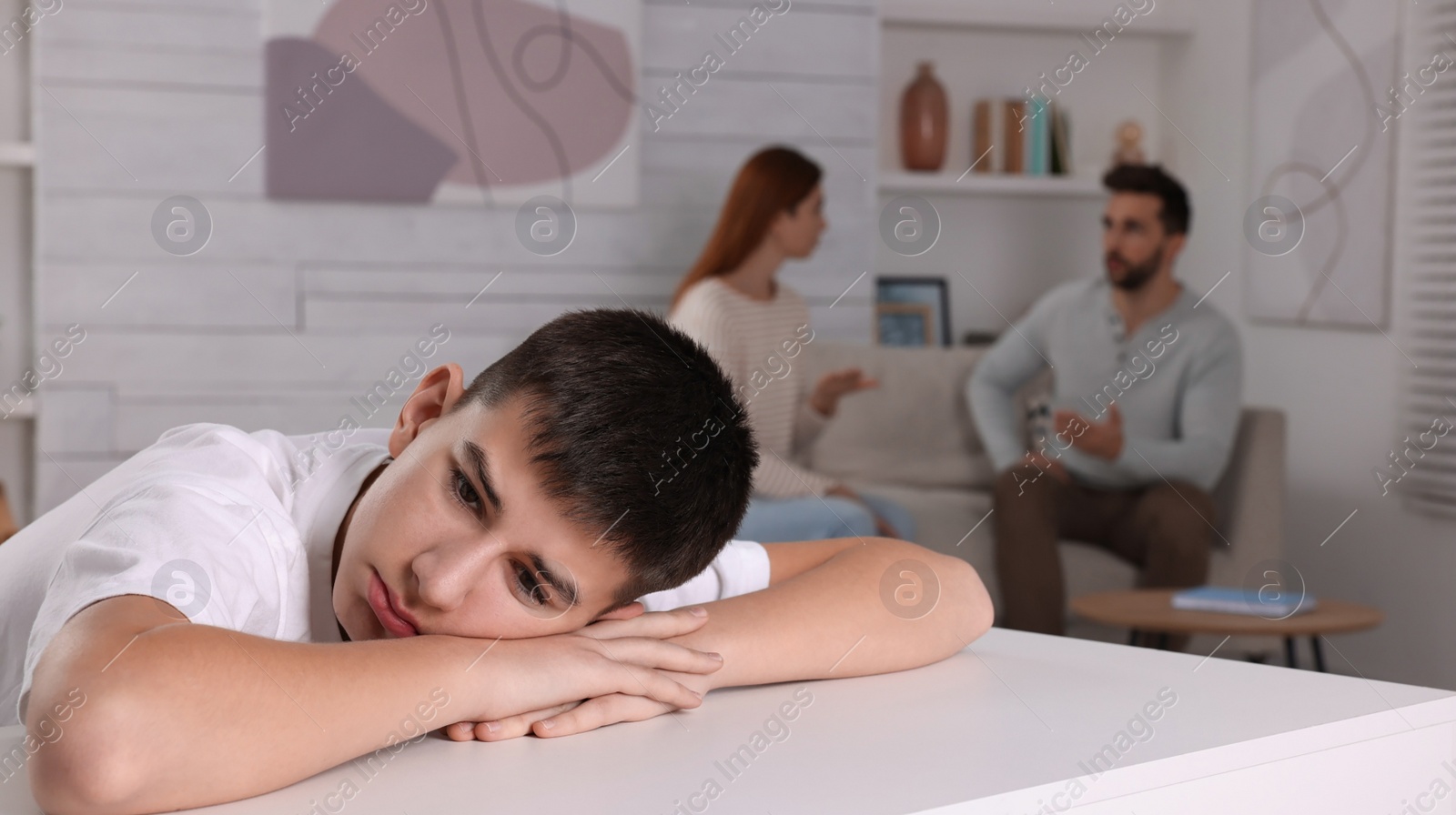 Photo of Couple arguing at home, focus on their unhappy teenage boy. Problems in family