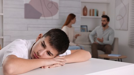 Couple arguing at home, focus on their unhappy teenage boy. Problems in family