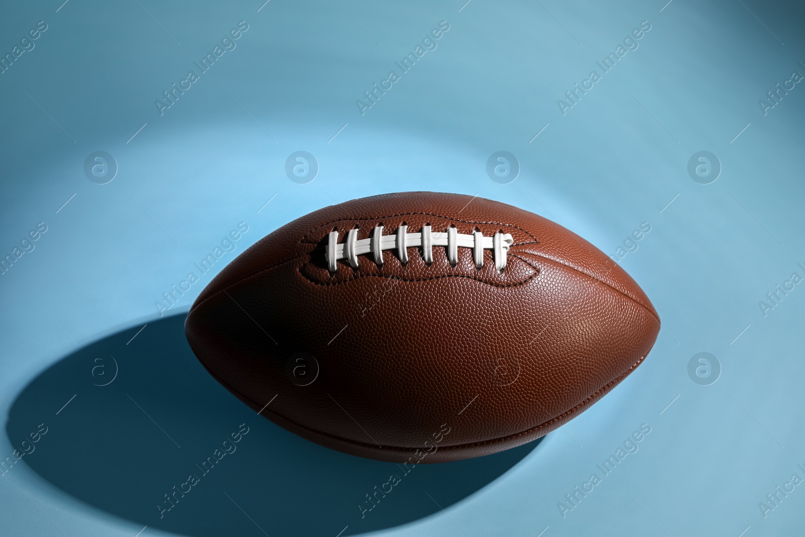 Photo of American football ball on light blue background