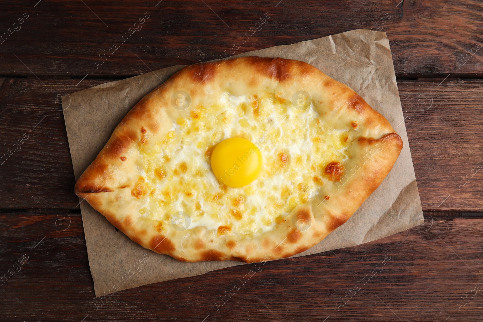 Photo of Fresh homemade khachapuri with cheese and egg on wooden table, top view