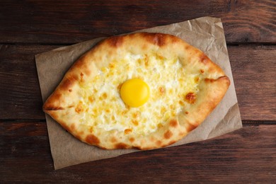 Fresh homemade khachapuri with cheese and egg on wooden table, top view