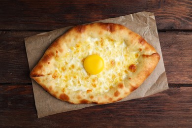 Photo of Fresh homemade khachapuri with cheese and egg on wooden table, top view