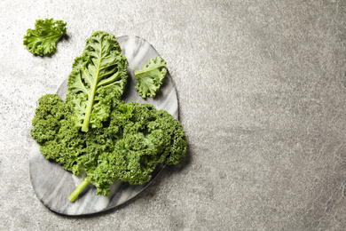 Fresh kale leaves on grey table, flat lay. Space for text