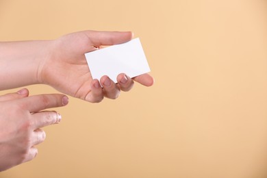 Man holding paper card on pale orange background, closeup. Mockup for design