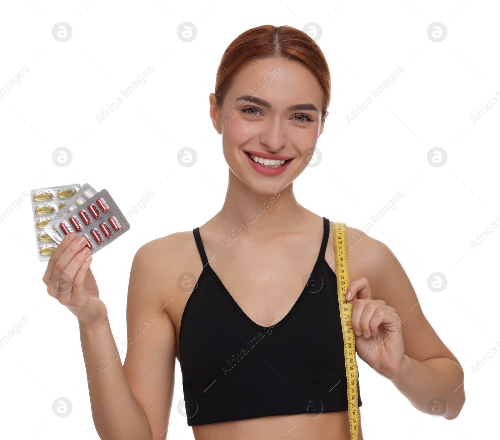 Photo of Happy young woman with pills and measuring tape on white background. Weight loss