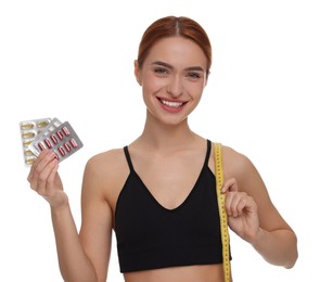 Photo of Happy young woman with pills and measuring tape on white background. Weight loss