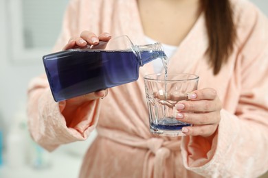 Photo of Young woman using mouthwash indoors, closeup view