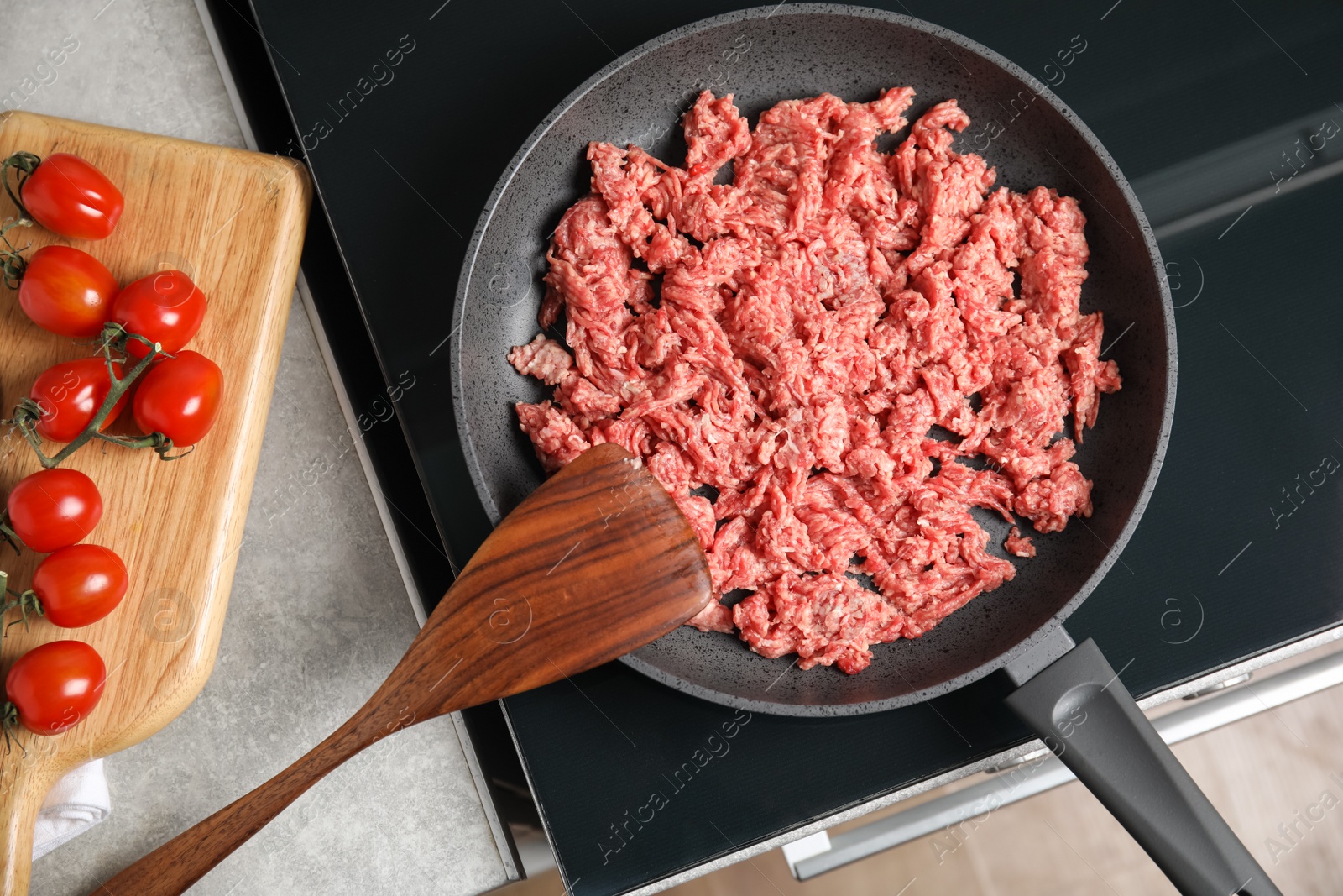 Photo of Frying pan with raw minced meat on induction stove indoors, flat lay