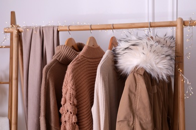 Photo of Rack with stylish warm clothes indoors, closeup